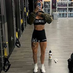 a woman taking a selfie while standing in a gym with her phone up to her ear