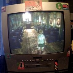 a small child is standing in front of a television set with the screen turned on