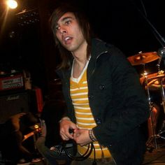 a man standing in front of a microphone on top of a drum set at night