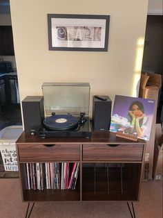 a record player sitting on top of a wooden table next to a shelf filled with records