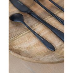 three black spoons are sitting on a wooden plate