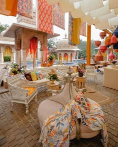 an outdoor seating area with lots of furniture and lanterns hanging from the ceiling over it