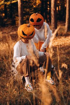 two children wearing pumpkin hats in the woods