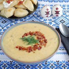 a bowl of potato soup with bacon and sour cream in the background on a blue tablecloth