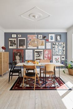 a dining room table with chairs and pictures on the wall behind it in front of an open door