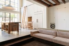 a living room filled with furniture next to a kitchen and dining area in front of large windows