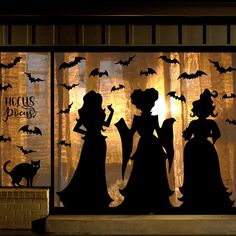 the silhouettes of two women and a cat are in front of a window decorated with bats