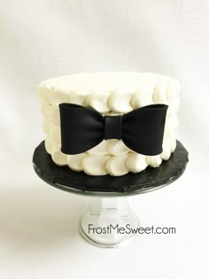 a white and black cake with a bow on top