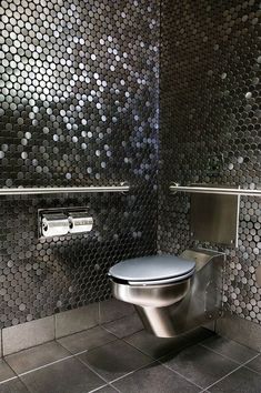 a metallic toilet in a bathroom with stainless steel walls and floor tiles on the wall