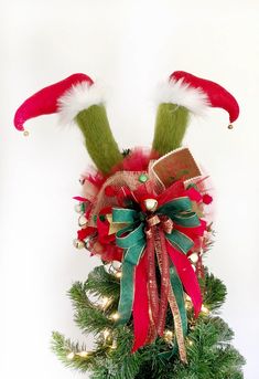 a green and red bow on top of a christmas tree with santa's hats