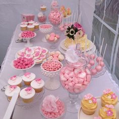 a table topped with lots of pink and white cupcakes