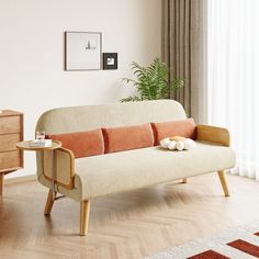 a living room with a white couch and wooden table next to a window on top of a hard wood floor