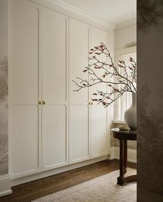 a vase with some flowers in it sitting on a table next to white cupboards