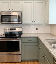 a kitchen with white cabinets and stainless steel appliances, including a microwave above the stove