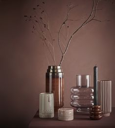 three vases with branches in them are sitting on a table next to each other