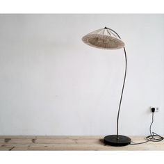 a lamp that is on top of a wooden floor in front of a white wall