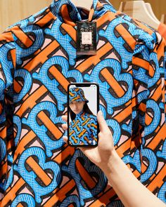 a person taking a photo of an orange and blue shirt