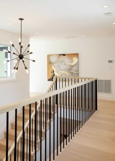 a staircase with black handrails leading up to a painting on the wall