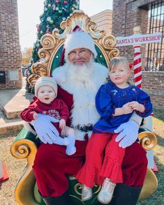 a santa clause sitting on top of a chair next to two children