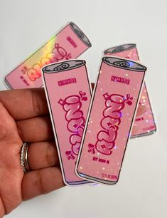 three pink stickers with the word coco cola written on them are held in someone's hand