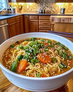 a bowl of noodles with carrots, green beans and sesame seeds on a wooden table