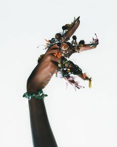 a person's hand holding several bracelets with flowers on each wrist and beads hanging from it