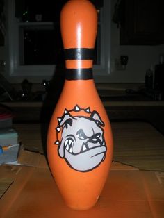 an orange bowling ball with a bulldog face painted on it's side sitting on a table