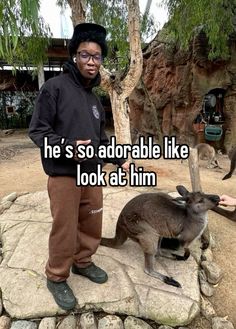 a man standing next to a kangaroo on top of a rock with the caption he's so adorable like look at him