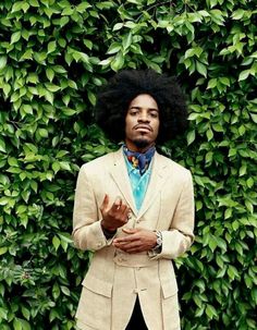 a man with an afro standing in front of a green wall