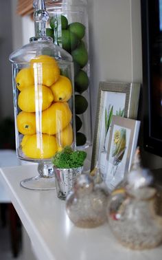 there are lemons and limes in the glass jar on the shelf next to the television