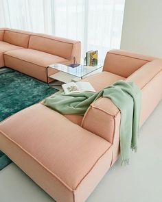 a living room filled with furniture and a green rug on the floor in front of a window