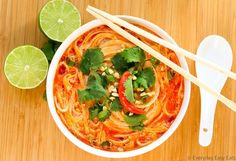 a bowl of noodles with cilantro and limes