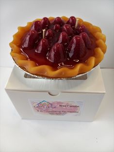 a pie with cherries on top sitting in a white box next to a sticker