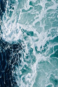 an aerial view of the ocean waves and foamy blue water, taken from above