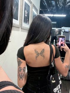 a woman taking a selfie in front of a mirror with tattoos on her back