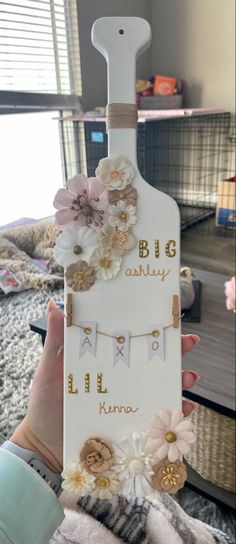 a person holding up a bottle with flowers on it and the words big brother written in gold