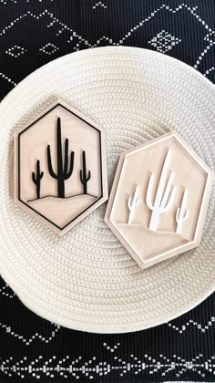 two wooden stamps sitting on top of a white plate next to a cactus and cacti