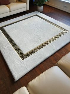 a living room with white furniture and a rug on the floor