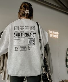 a woman with her back turned to the camera wearing a sweatshirt that says skin therapy