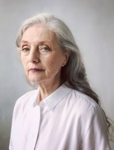 an older woman with grey hair and white shirt looking off to the side, in front of a gray background