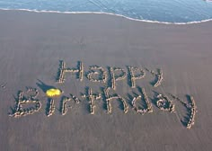 happy birthday written in the sand at the beach