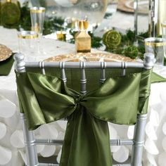 a green chair sash is tied to the back of a silver chair at a formal dinner table