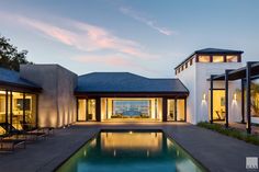 an outdoor swimming pool next to a large house with glass doors and windows on both sides