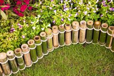 several bamboo poles are arranged in the shape of a circle on grass with flowers behind them