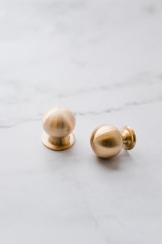 two gold knobs on a white marble surface