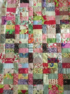 a quilt made with many different colors and patterns on the fabric, including pink, green,