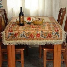 a dining room table and chairs with a placemat on it, next to a bottle of wine