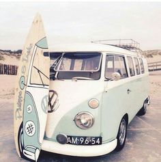 an old vw bus parked on the beach with a surfboard