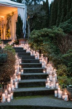 many lit candles are on the steps leading up to an outdoor area with trees and bushes