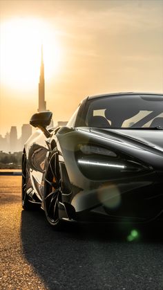 the front end of a black sports car on a city street with skyscrapers in the background